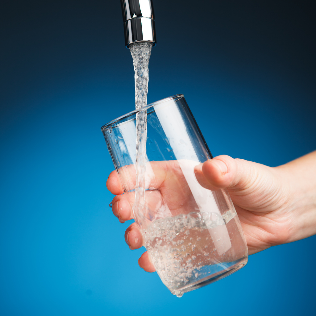 Someone getting water in their glass from a tap filter